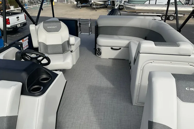 Slide: The Image of 2026 Crest Conquest SE 220 Cruise pontoon boat interior with gray seating and steering console. - 12