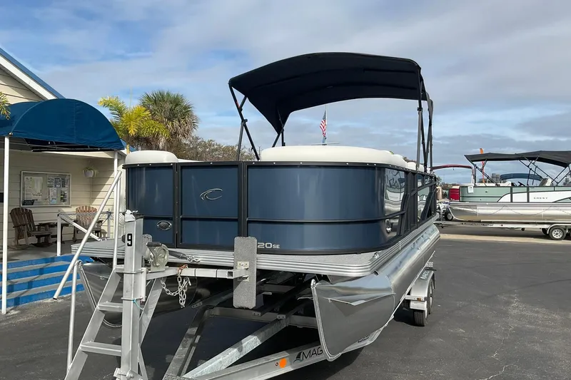 Slide: The Image of 2026 Crest Conquest SE 220 Cruise pontoon boat on trailer, parked outdoors. - 2