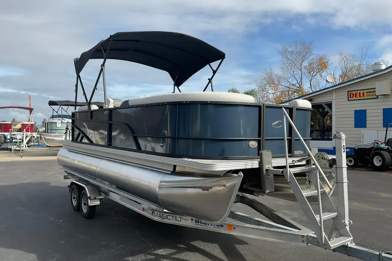Slide: The Image of 2026 Crest Conquest SE 220 Cruise pontoon boat on trailer, parked near a deli. - 5