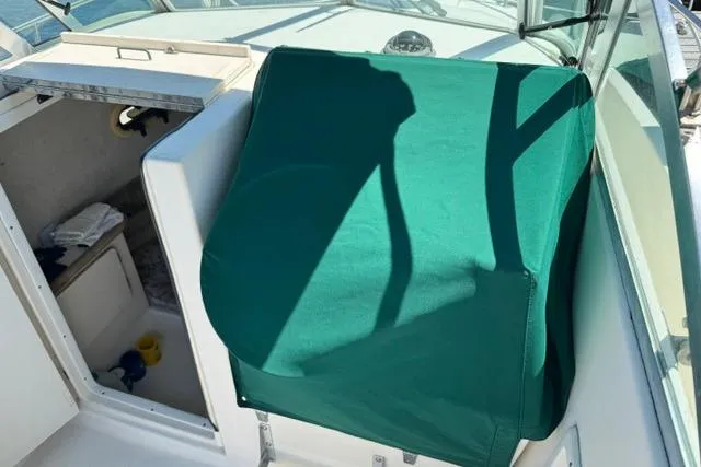 Slide: The Image of 2000 Pursuit 2470 Walkaround boat interior with green cover and cabin entrance. - 10