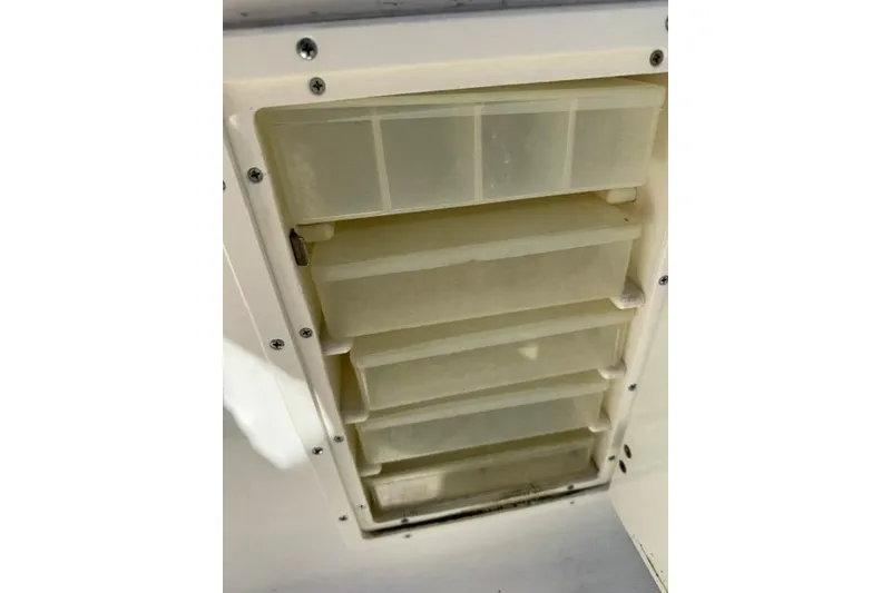 Slide: The Image of Storage compartment with multiple plastic drawers on a 2000 Pursuit 2470 Walkaround boat. - 11