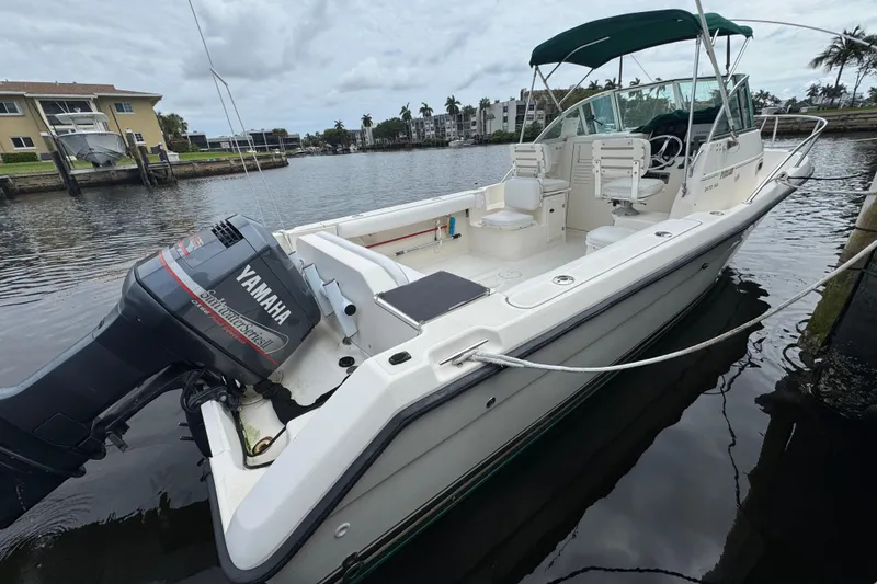 Slide: The Image of 2000 Pursuit 2470 Walkaround boat with Yamaha outboard motor docked in a marina. - 2