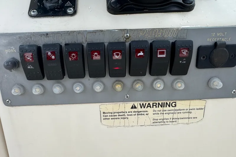 Slide: The Image of Control panel of a 2000 Pursuit 2470 Walkaround boat with switches and warning label. - 23