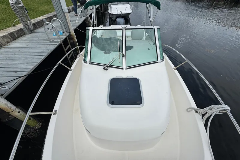 Slide: The Image of 2000 Pursuit 2470 Walkaround boat docked, featuring a white deck and windshield. - 4
