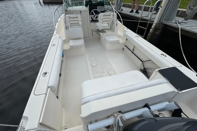 Slide: The Image of 2000 Pursuit 2470 Walkaround boat with spacious deck and seating, docked by the water. - 5