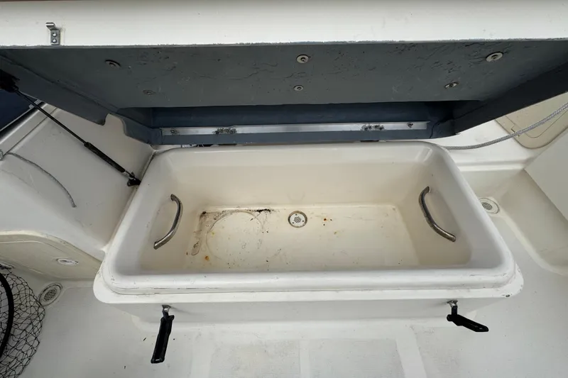 Slide: The Image of Open storage compartment on a 2000 Pursuit 2470 Walkaround boat, featuring metal handles. - 7
