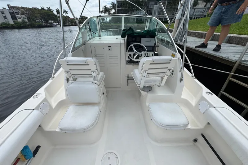 Slide: The Image of 2000 Pursuit 2470 Walkaround boat interior with seating and steering wheel by the water. - 8