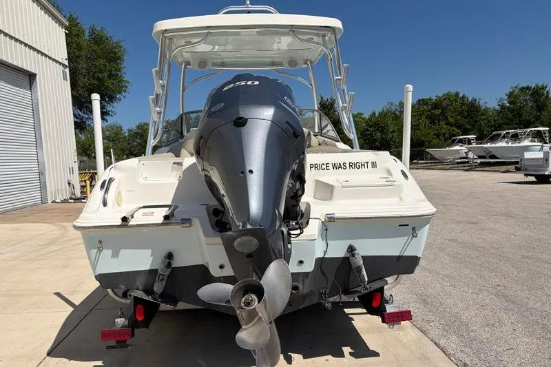 Slide: The Image of 2023 Key West 239 DFS boat with outboard motor, parked outdoors on a sunny day. - 10