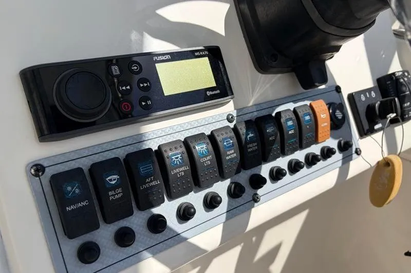 Slide: The Image of Control panel of a 2023 Key West 239 DFS boat with various switches and a Fusion stereo. - 21