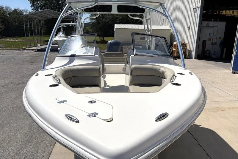 Slide: The Image of 2023 Key West 239 DFS boat with spacious seating, docked outdoors near a warehouse. - 6