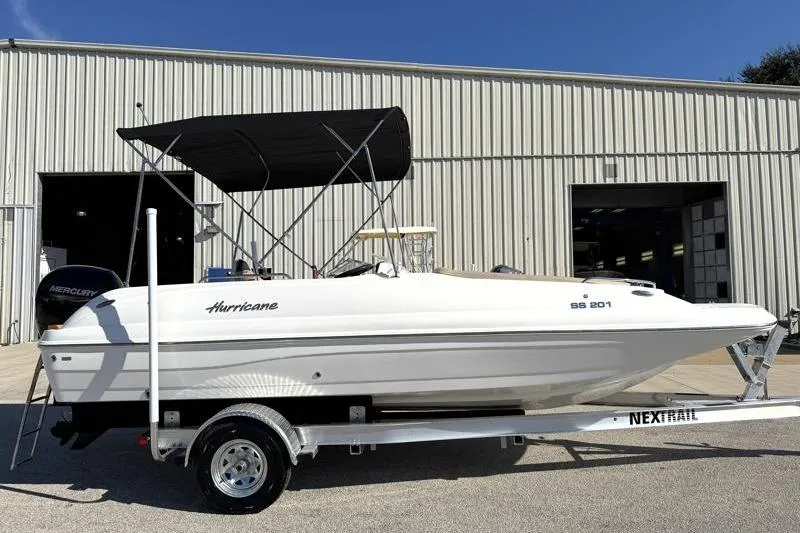 The Image of 2022 Hurricane SunDeck Sport 201 OB boat on trailer, parked outside a warehouse. - 0