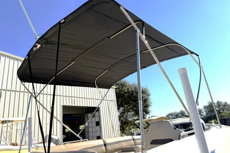 Slide: The Image of 2022 Hurricane SunDeck Sport 201 OB boat with black canopy under clear blue sky. - 9