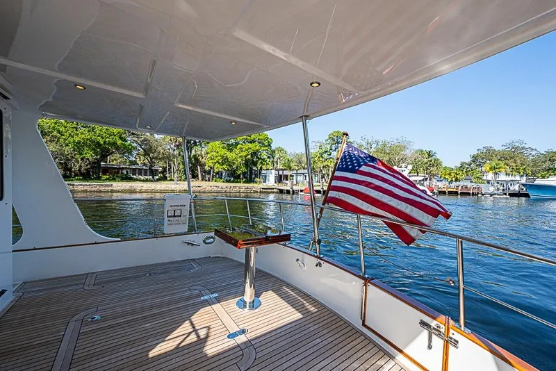 Slide: The Image of 2013 Grand Banks 43 Europa yacht deck with American flag, overlooking serene waterfront. - 10