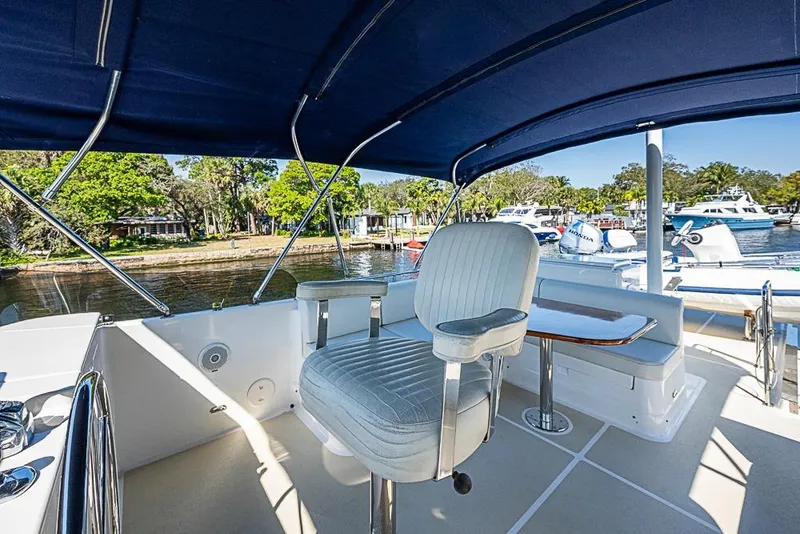 Slide: The Image of Flybridge of 2013 Grand Banks 43 Europa yacht with seating and table, docked by lush greenery. - 22