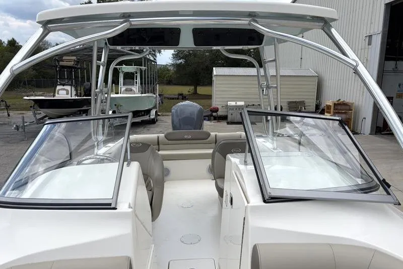 Slide: The Image of 2024 Key West 239 DFS boat interior with seating and windshield, parked outdoors. - 20