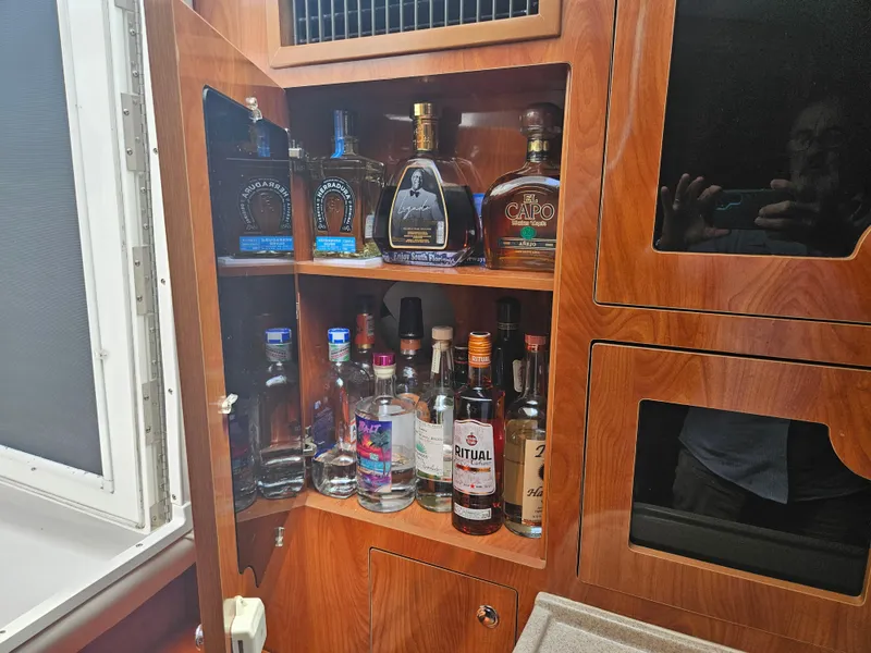 Slide: The Image of Liquor cabinet inside a 2005 Four Winns 378 Vista boat, featuring various bottles. - 29
