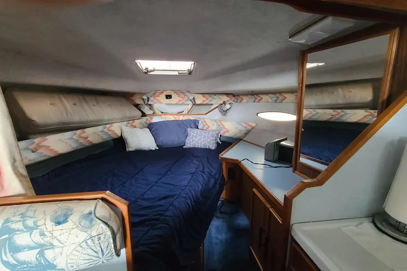 Slide: The Image of Interior cabin of a 1987 Sea Ray 300 Sundancer with cozy bedding and nautical decor. - 12