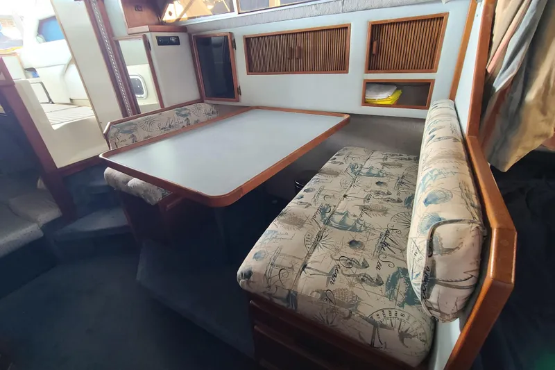 Slide: The Image of 1987 Sea Ray 300 Sundancer cabin with dining area, featuring patterned seating and wooden accents. - 14