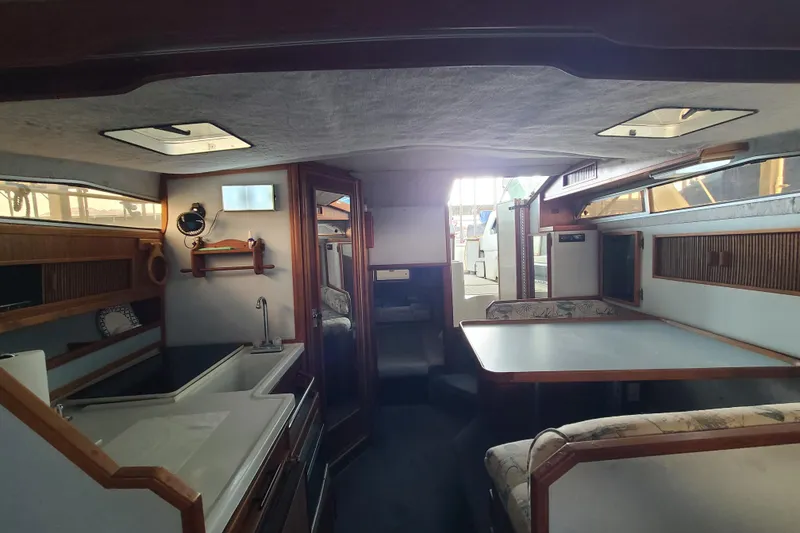 Slide: The Image of Interior of a 1987 Sea Ray 300 Sundancer boat, featuring a cozy dining area and kitchenette. - 15
