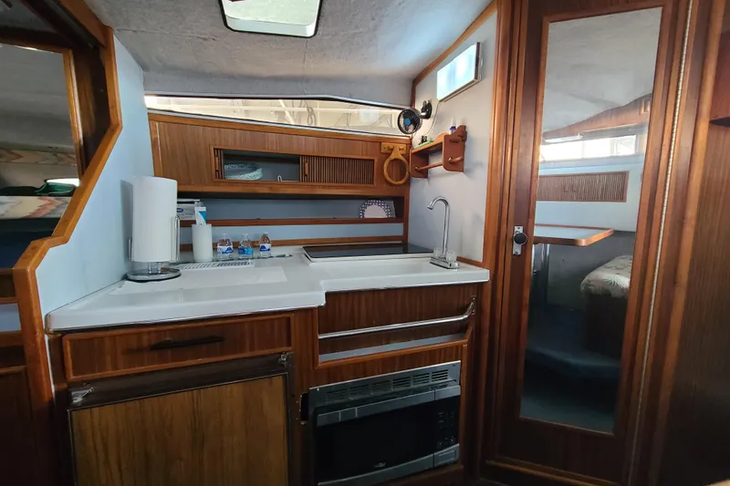Slide: The Image of Interior of 1987 Sea Ray 300 Sundancer boat with kitchenette and wood accents. - 16