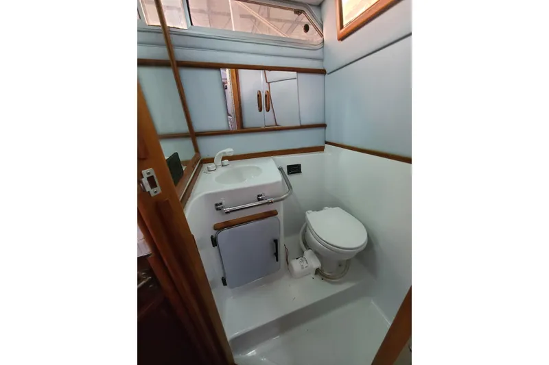 Slide: The Image of 1987 Sea Ray 300 Sundancer bathroom with toilet, sink, and mirror. - 18