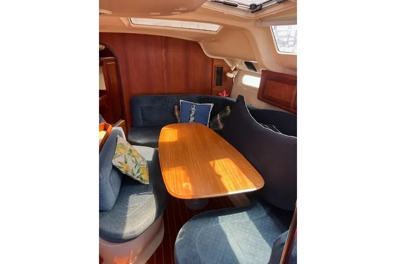 Slide: The Image of Cozy interior of a 1997 Hunter 430 sailboat with wooden table and blue seating. - 25