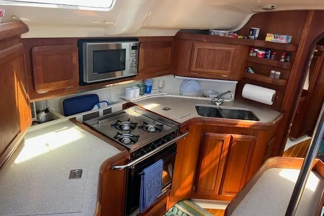 Slide: The Image of 1997 Hunter 430 yacht kitchen with stove, microwave, and wooden cabinetry. - 27