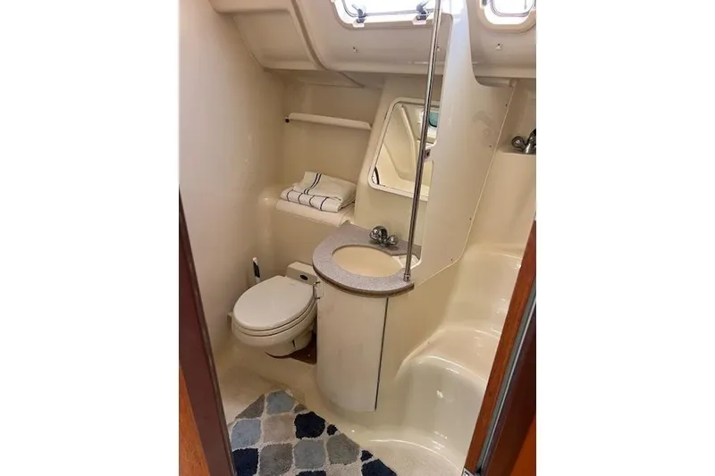 Slide: The Image of Compact bathroom in a 1997 Hunter 430 sailboat, featuring a toilet, sink, and mirror. - 28