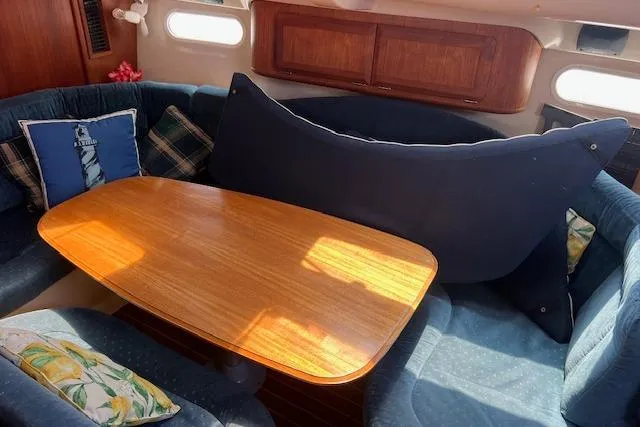Slide: The Image of Interior of a 1997 Hunter 430 sailboat with a cozy dining area and cushions. - 29