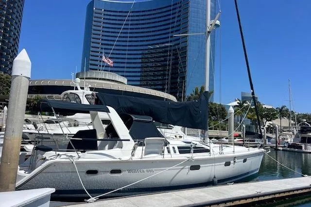 Slide: The Image of Hunter 430 sailboat from 1997 docked in a marina with modern buildings in the background. - 6