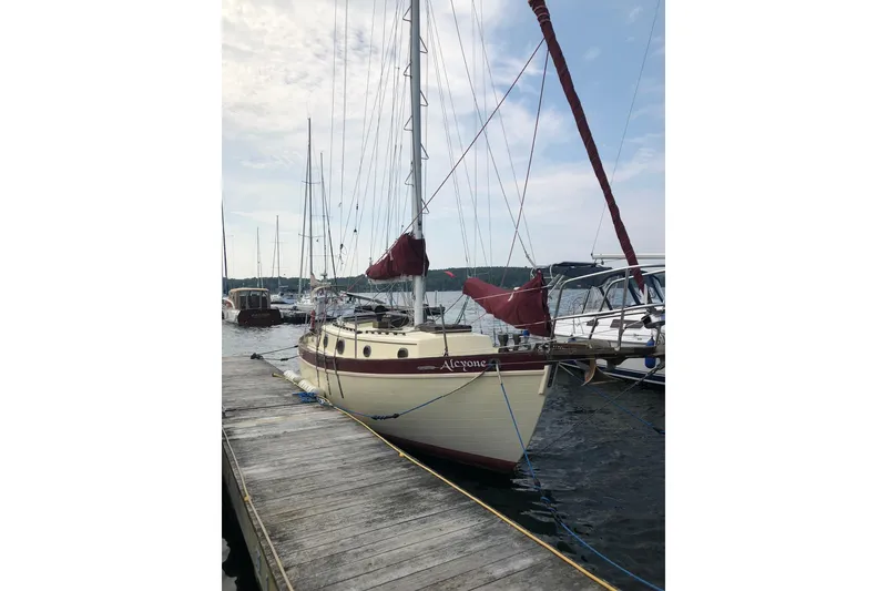 The Image of 1978 Pacific Seacraft 31 sailboat docked at marina, featuring classic design and maroon sails. - 0