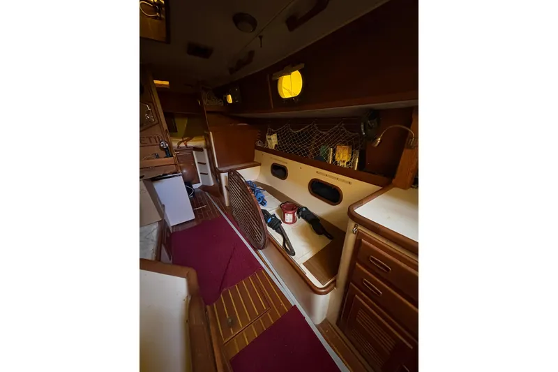 Slide: The Image of Interior of 1978 Pacific Seacraft 31 sailboat, featuring wooden cabinetry and cozy seating area. - 18
