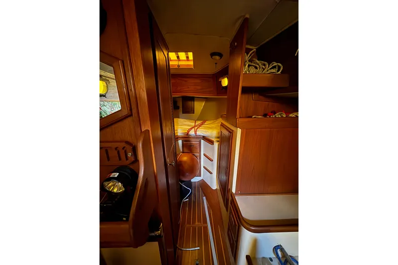 Slide: The Image of Interior of a 1978 Pacific Seacraft 31 sailboat, featuring wooden cabinetry and cozy sleeping quarters. - 20