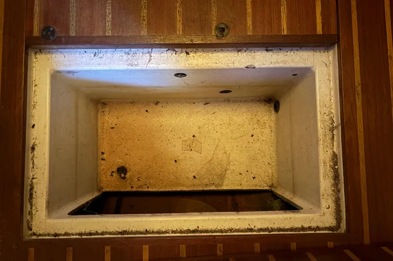 Slide: The Image of Empty storage compartment on a 1978 Pacific Seacraft 31 boat, featuring wooden trim. - 37