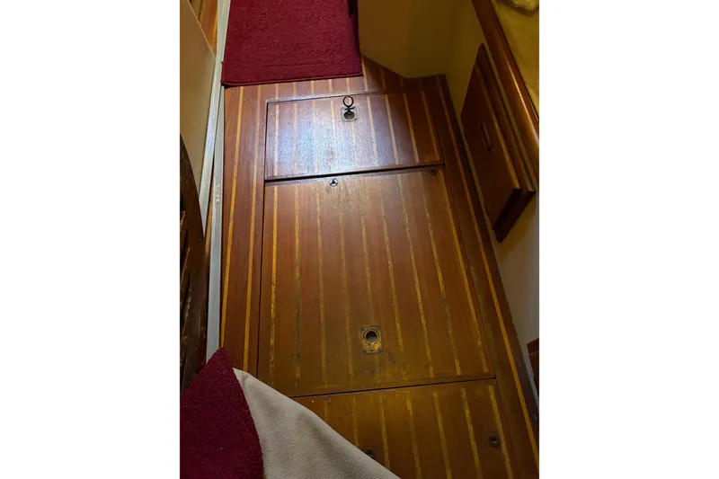 Slide: The Image of Wooden cabin floor of 1978 Pacific Seacraft 31 sailboat with red carpet accents. - 38