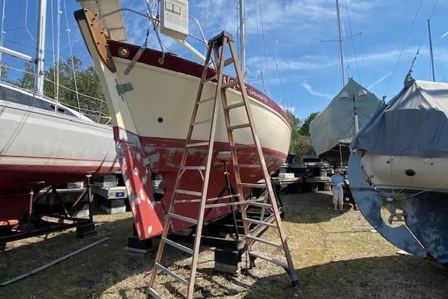 Slide: The Image of 1978 Pacific Seacraft 31 sailboat on dry dock with ladder, surrounded by other boats. - 5