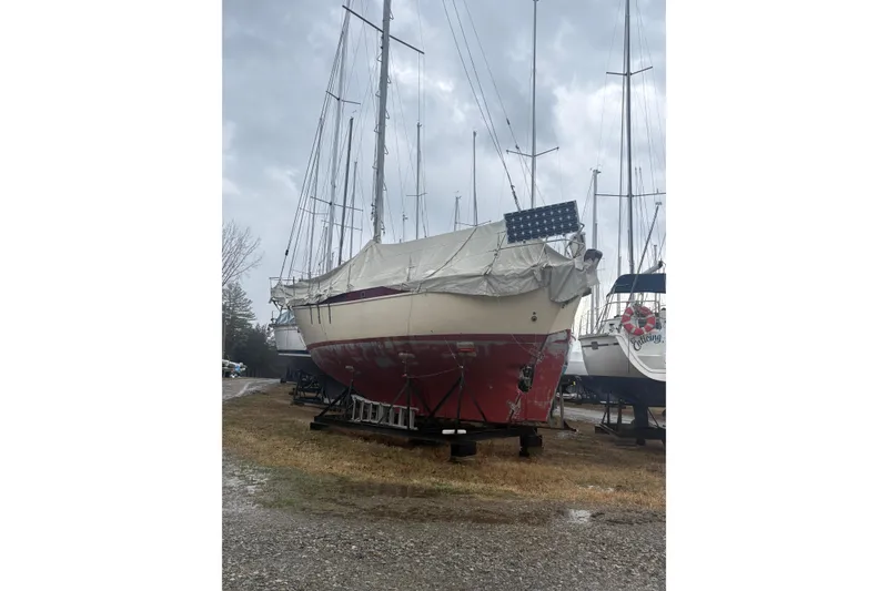 Slide: The Image of 1978 Pacific Seacraft 31 sailboat on land, covered, with red hull and solar panel. - 6