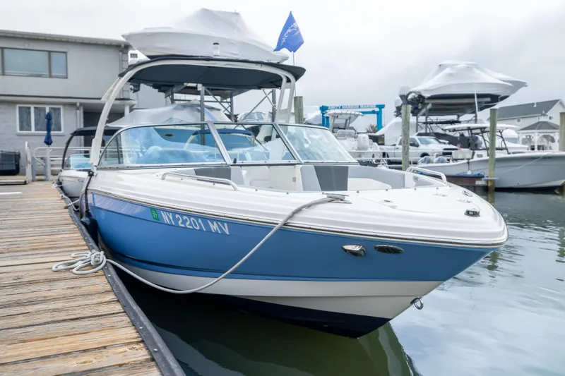 Slide: The Image of 2024 Chaparral 23 SSi OB boat docked, featuring sleek blue and white design. - 21