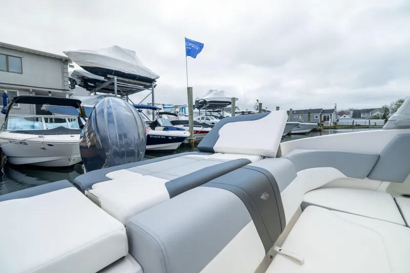 Slide: The Image of 2024 Chaparral 23 SSi OB boat with sleek seating, docked at a marina. - 9