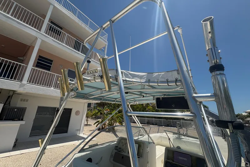 Slide: The Image of 2002 World Cat 246 DC boat with metal framework and rod holders, docked near a building. - 13