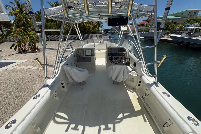 Slide: The Image of 2002 World Cat 246 DC boat interior with helm, seating, and canopy in a marina setting. - 7