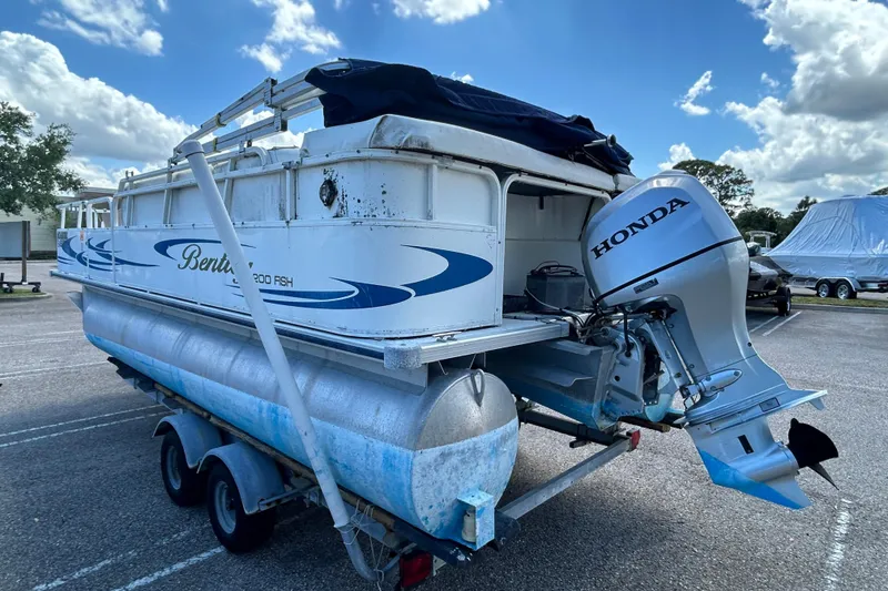 Slide: The Image of 2005 Bentley Pontoons 200 Fish with Honda outboard motor on trailer, parked outdoors. - 2