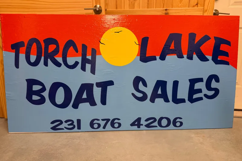 Slide: The Image of Colorful Torch Lake Boat Sales sign with contact number, featuring a sun graphic. - 12