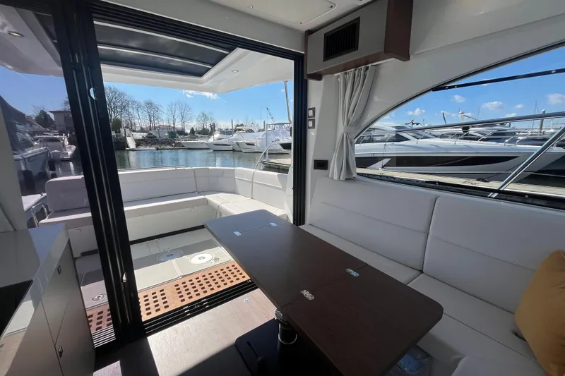 Slide: The Image of Interior view of 2026 Beneteau Antares 11 Coupe, featuring spacious seating and waterfront backdrop. - 10
