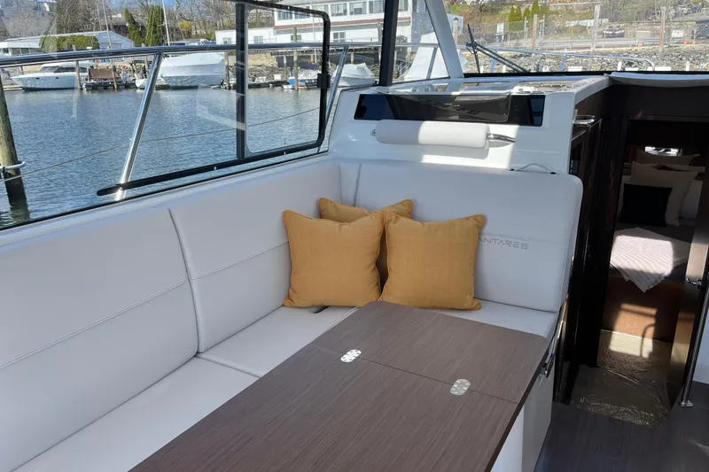 Slide: The Image of Interior of 2026 Beneteau Antares 11 Coupe with white seating and yellow cushions. - 11
