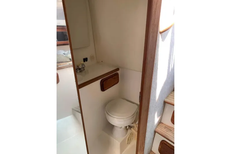 Slide: The Image of 1998 Contender 35 Express Side Console boat bathroom interior with toilet and wooden accents. - 11