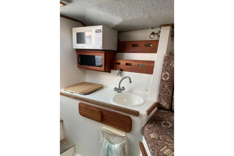Slide: The Image of Compact kitchen area in a 1998 Contender 35 Express Side Console boat with sink and microwave. - 14