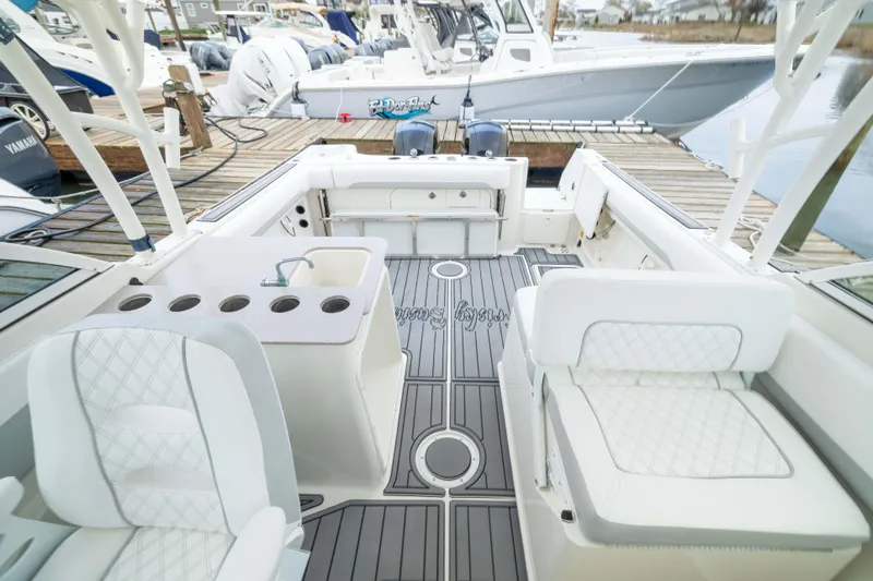 Slide: The Image of Interior of a 2014 Sailfish 275 DC boat with white seating and a docked view. - 12