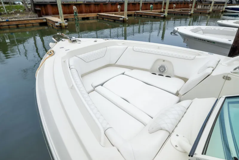 Slide: The Image of 2014 Sailfish 275 DC boat with white cushioned seating in a marina. - 16