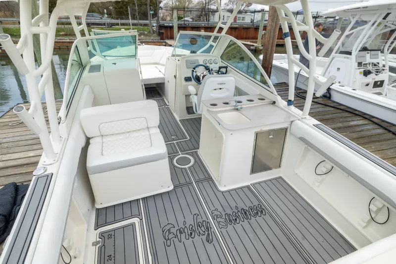 Slide: The Image of 2014 Sailfish 275 DC boat interior with seating, helm, and sink at dock. - 3